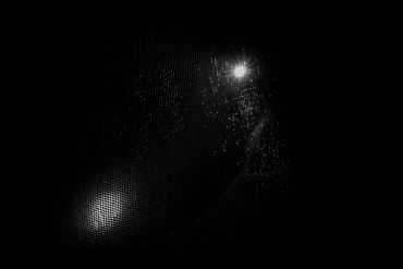 Dark scene with faint light reflections and textured patterns.