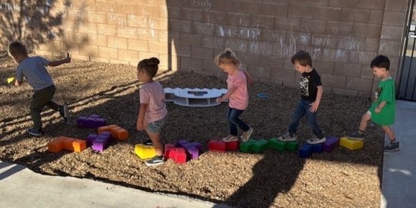 Children walking on colorful blocks in playground.