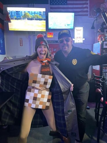 Two people posing in a bar, one dressed in a pixelated costume and the other as security.