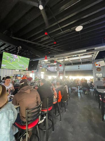 Busy bar with patrons watching football on TV and socializing.