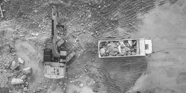 Aerial view of excavator loading rocks into a dump truck at a construction site.