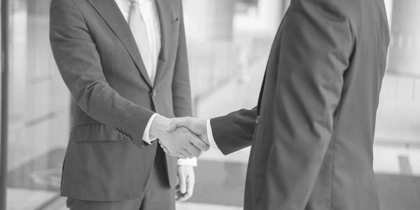 Two businessmen shaking hands in a formal setting.