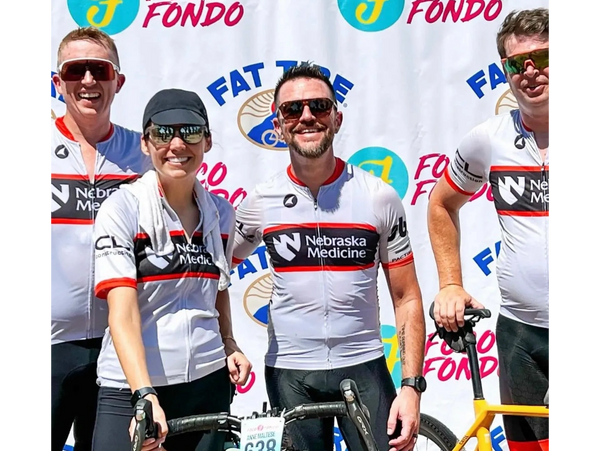 Four cyclists in Nebraska Medicine outfits pose with bikes at a Foco Fondo event.