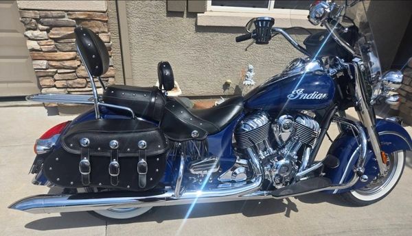 Blue Indian motorcycle with leather saddlebags and two seats.