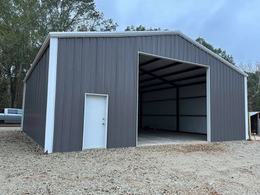 Newly constructed metal building with an open garage door and side entry door.