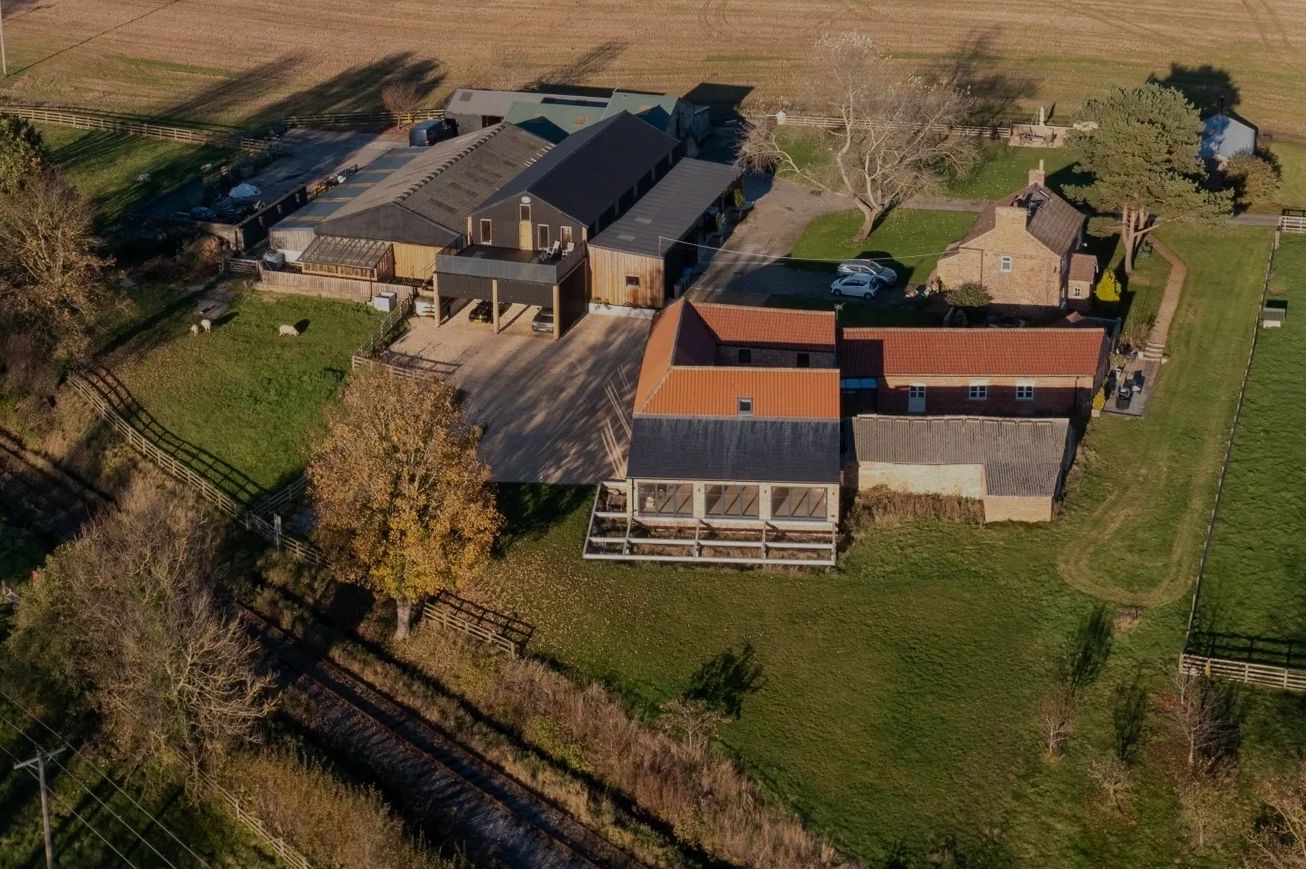 Aerial view of a rural farmhouse and outbuildings surrounded by fields.