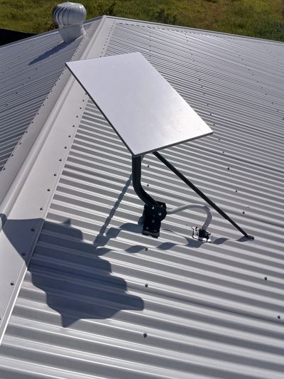 A solar panel mounted on a corrugated metal roof under sunlight.