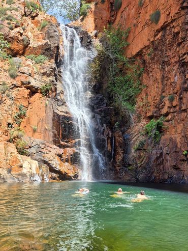 Tourists swim under a beautiful waterfall on a Silent Tour Ord River Eco-CRuise