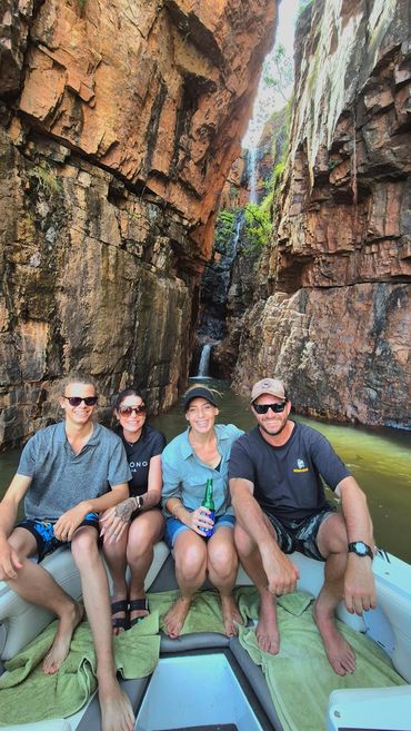 Silent Tours Boat next to waterfall with four passengers smiling