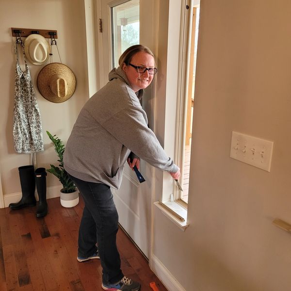 A person using a measuring tape on a door frame indoors.
