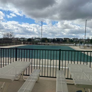 Covered outdoor pool with cloudy sky and empty chairs.