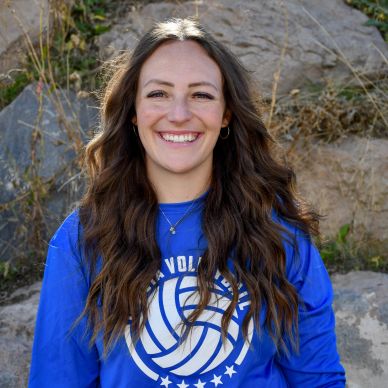 Smiling woman with long hair in blue sports shirt outdoors.