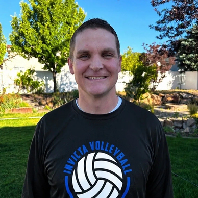 Man smiling outdoors in a volleyball shirt.