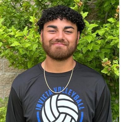 Young man in volleyball shirt smiles outdoors.
