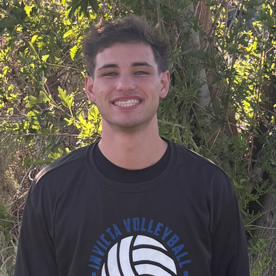 Young man smiling outdoors in volleyball shirt.