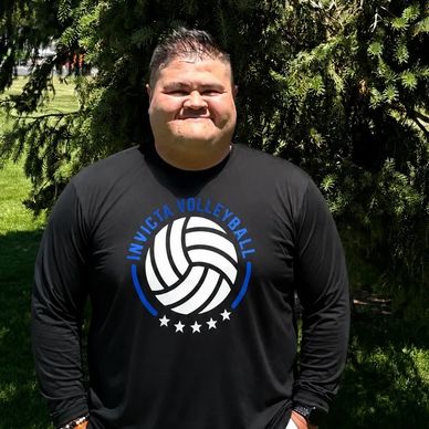 Smiling man in a black volleyball shirt outdoors.