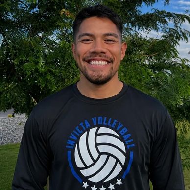 Smiling man outdoors wearing a volleyball shirt.