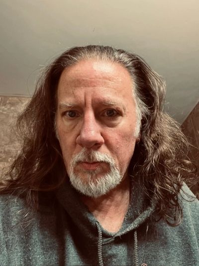 Portrait of a man with long hair and a white beard.