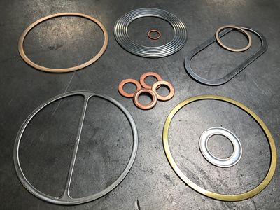 Various metal and rubber gaskets arranged on a surface.