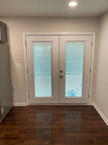 White double doors with blinds and dark wooden floor inside a room.