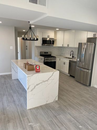Modern kitchen with marble island and stainless steel appliances.