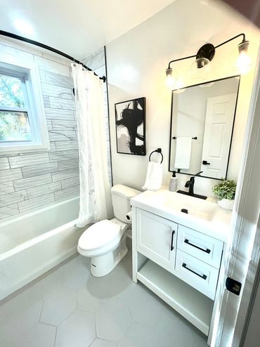 Bright modern bathroom with white fixtures and black accents.