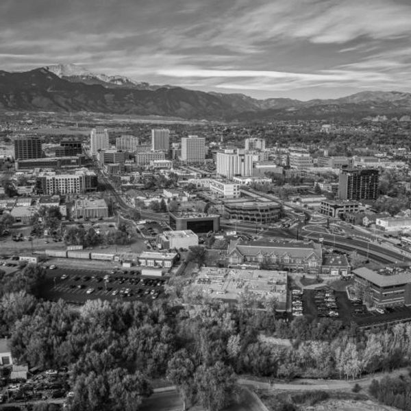 Black and white aerial view of a city with mountains in the background.