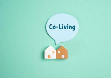 Two small house models with a speech bubble saying 'Co-Living'.