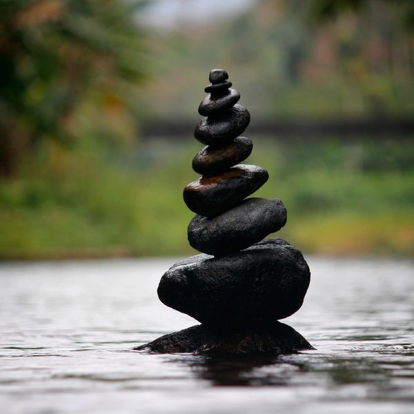 A balanced stack of smooth black stones rising from calm water.