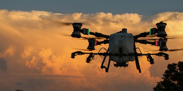 A drone flying at sunset with glowing lights and dramatic clouds.