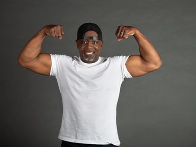 Man in white shirt flexing muscles with a smile.