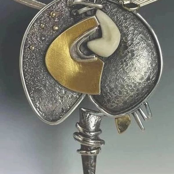 Abstract metallic pendant with gold and red accents.