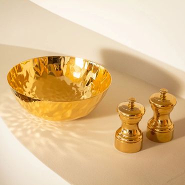 Bol dorado de Alessi y molinillos dorados de Peugeot