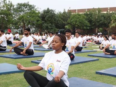 Group yoga session at Chandigarh University on a grassy field.