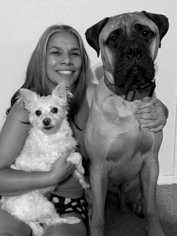 Woman smiling with two dogs of different sizes.