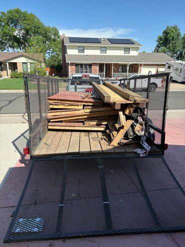 Loaded trailer with old wooden boards in a residential driveway.