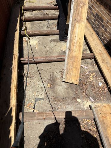 Wooden beams being installed for a deck or floor frame.