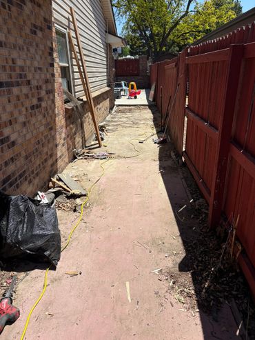 Side yard with red fence and children's toy car at the end.