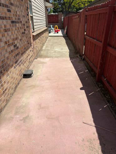 Narrow backyard alley with a red wooden fence and children's toy car.