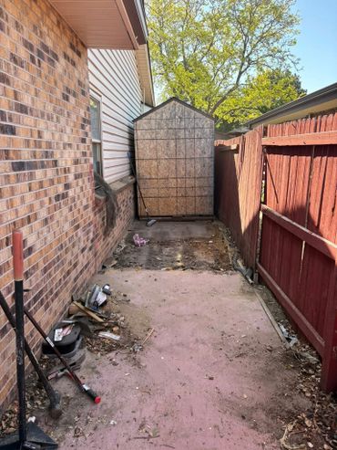 Narrow backyard space with a shed and tools scattered around.