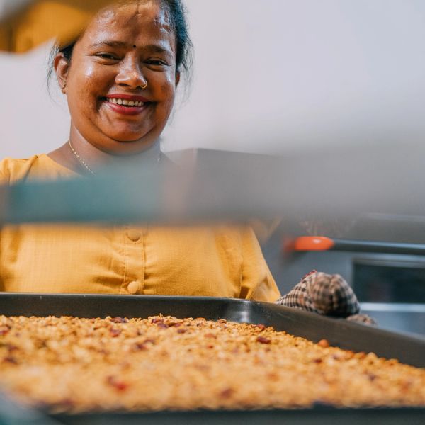 Woman smiling with a tray of baked food.