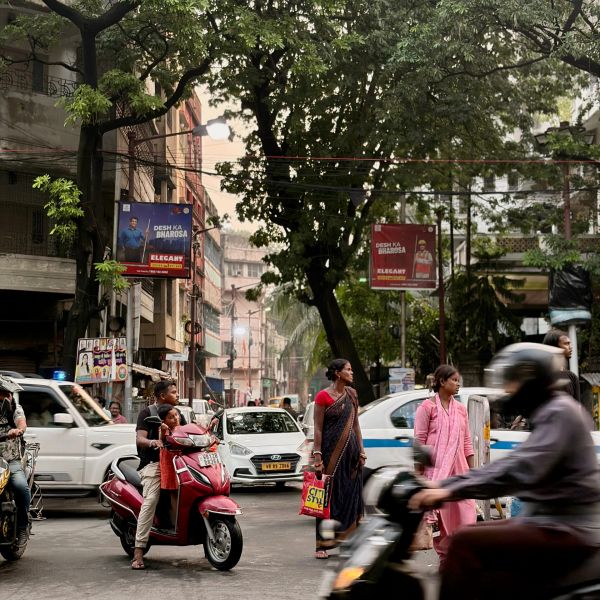 Busy street scene with people, scooters, and cars in India.