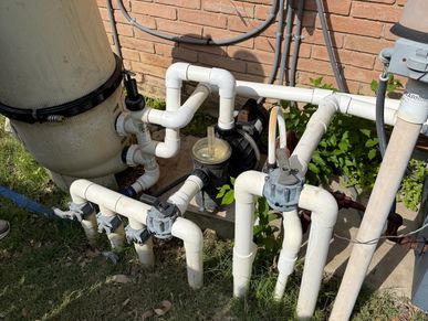Outdoor water filtration or pool pump system with pipes.