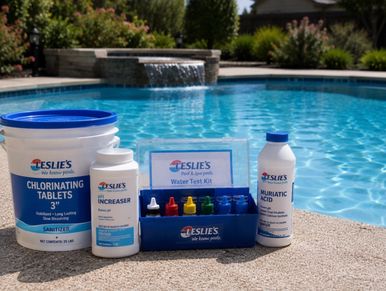 Pool water treatment chemicals and test kit beside a swimming pool.