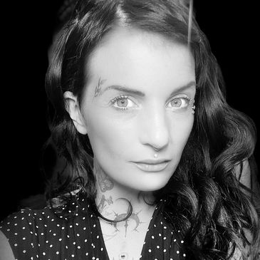 Portrait of a woman with tattoos and piercings in a polka dot dress.