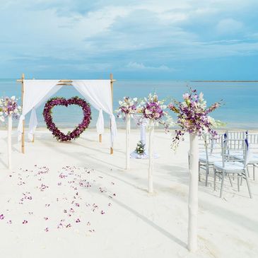 Beach setting with floral heart backdrop for Humanist wedding with English Celebrant Susan Dobinson