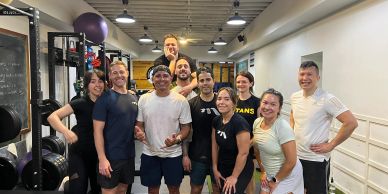 Group of people posing happily in a gym.