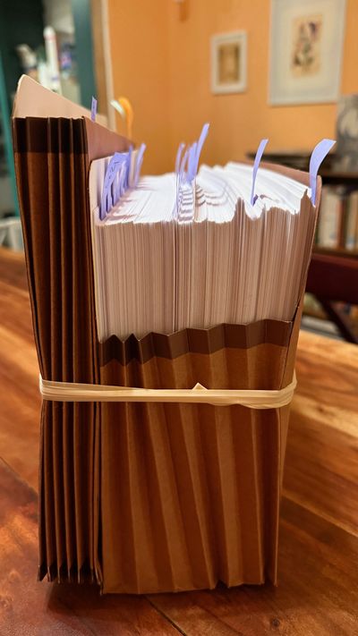 Thick stack of documents bound with a rubber band and marked with blue tabs.