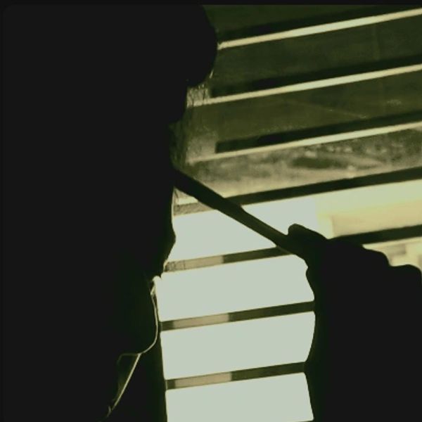 Silhouette of a person smoking near window blinds with light filtering through.