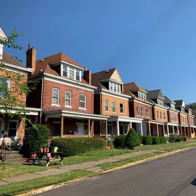 Row of colorful brick townhouses under clear blue sky.
